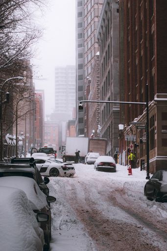 A vertical shot of snowy street with parking snowy and high buildings in Montreal, Canada