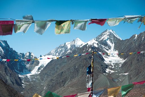 The prayer flags in Kunzum pass with the mountains covered in snow in the background