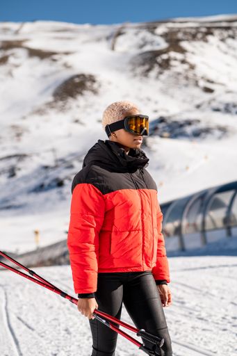 A African American woman with ski poles standing on snowy mountain during winter