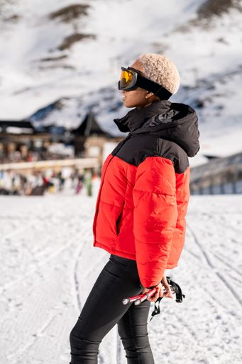 A African American woman with ski poles standing on snowy mountain during winter