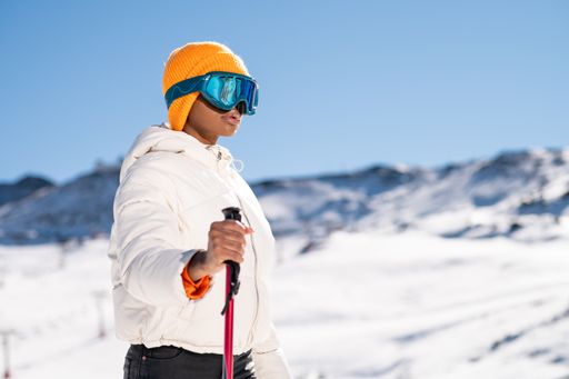 A African American woman with ski poles standing on snowy mountain during winter