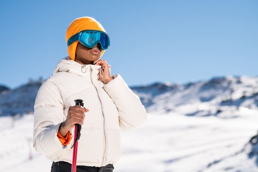 A African American woman with ski poles standing on snowy mountain during winter