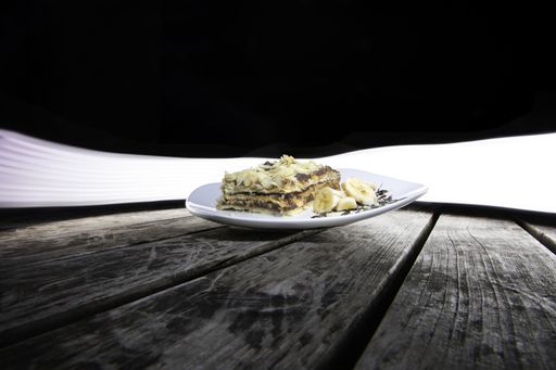 A shot of a yummy piece of cake with bananas on a plate on a wooden table