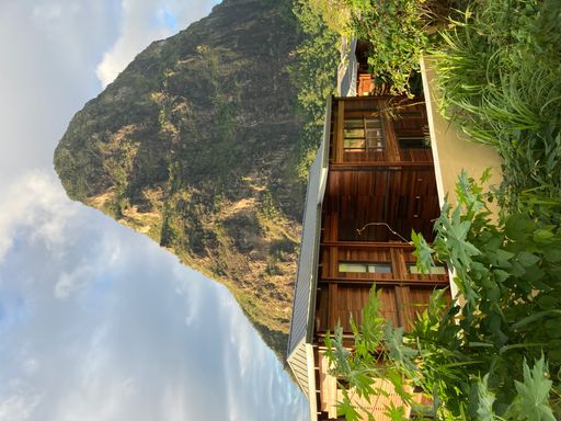 A vertical shot of a wooden building under the mountain peak