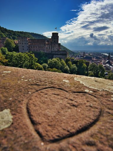 A closeup shot of the heart shape on the sand with Heidelberg castle background in Germany