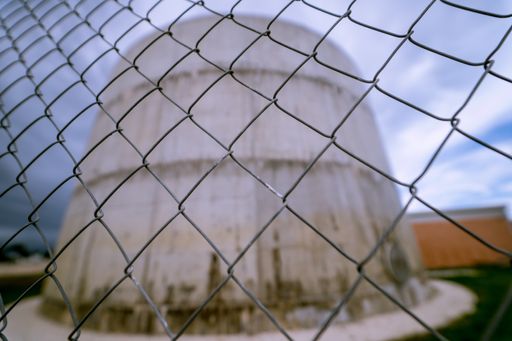 A selective focus shot of an industrial concrete building behind the metal fence