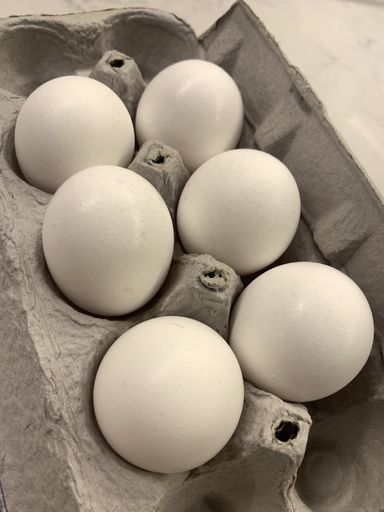 A close up shot of six eggs in an egg carton box