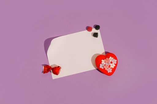 A creative layout made of fruity sweets and red heart with little flowers on purple background