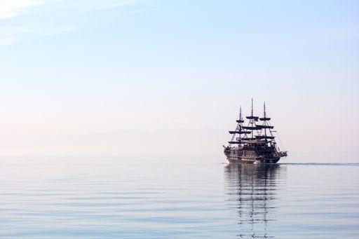 A horizontal shot of a tall ship sailing on beautiful clear water during daylight