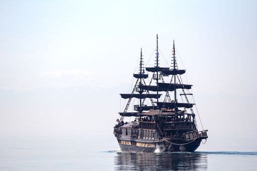 A horizontal shot of a tall ship sailing on beautiful clear water during daylight