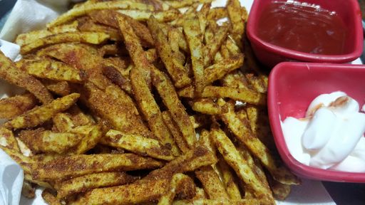 A close up shot of seasoned fries with ketchup and mayonnaise