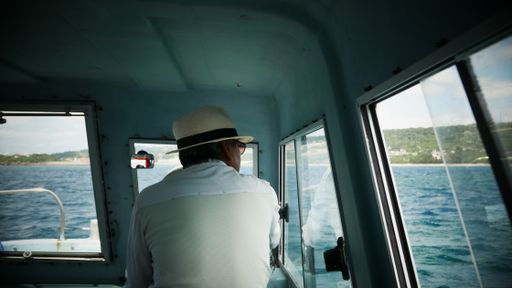 A rear view of a male captain drive his lovely boat in Okinawa, Japan