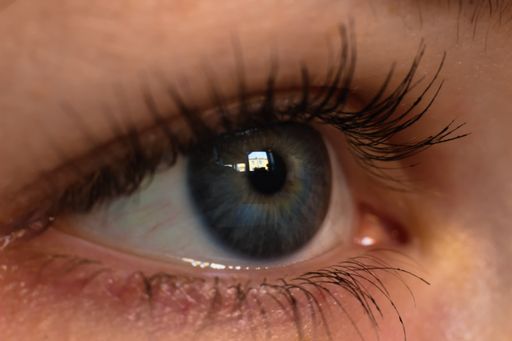 A closeup shot of a woman's blue eye and the eyelashes