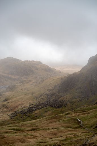 A vertical shot of misty mountains under stormy clouds