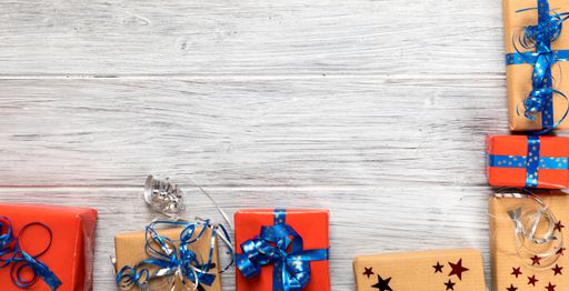 A flat lay of Christmas gifts on a white painted wooden surface with copy space