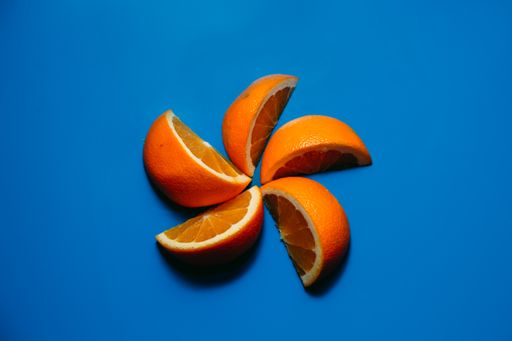 A top view of orange slices forming a flower shape isolated on a blue background