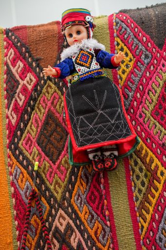 A closeup shot of a small doll with woolen clothes on a colorful surface