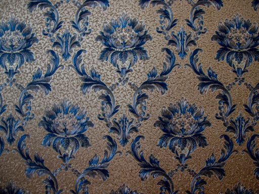 A closeup shot of wall wallpaper with a blue flower pattern