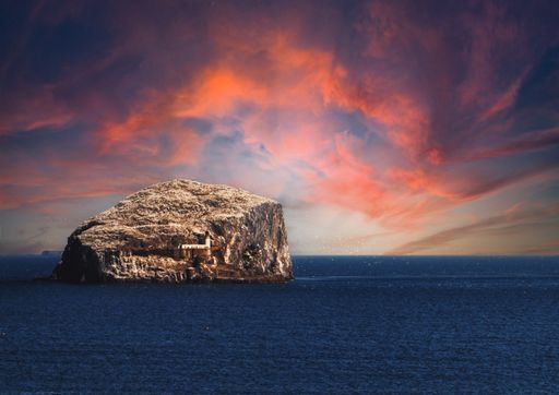 A beautiful shot of a bass rock with the sunset in a background