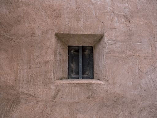 A closeup shot of an old small window in a concrete wall