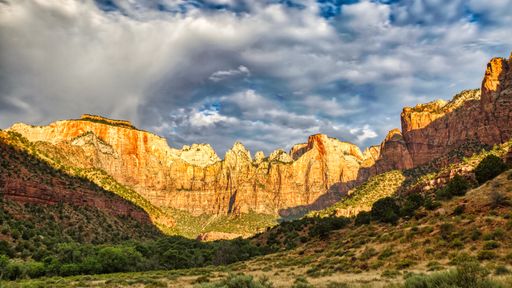 A scenic view of sunlight hitting the rocky mountains of the Towers of the Virgin in Zion National Park, Utah