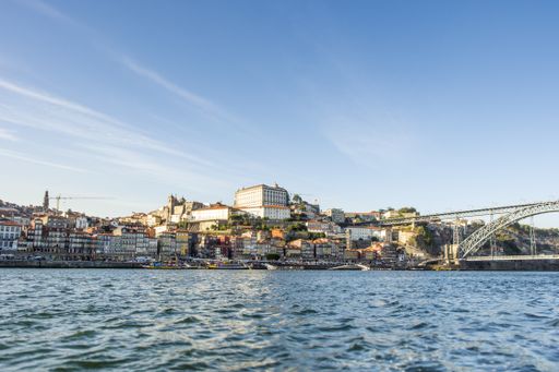 A low angle view of a river with a bridge and cityscape on a sunny day