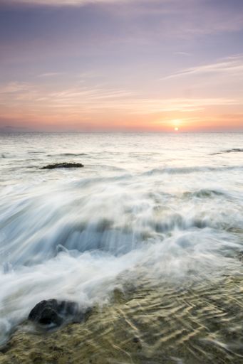 A long exposure shot of the waves of the ocean during sunset