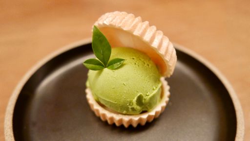 A closeup shot of a green ice-cream scoop served with the cookie on the black plate