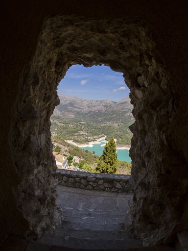A vertical view of the Guadalest Reservoir from a rocky arch under the sunlight in Spain