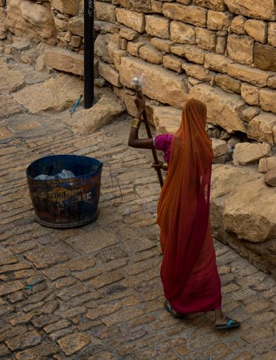 A view of female in sari sweeper cleaning golden stone ground in street