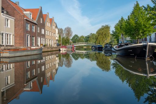A horizontal shot of a beautiful canal with boats and houses surrounding it
