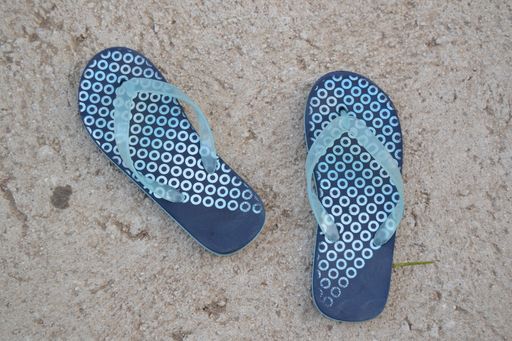 A top view of blue beach flip flops on ground