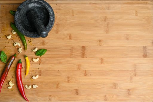 A top view of colorful peppers, mortar and pestle on a wooden table with a copy space