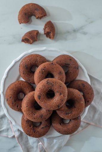 A top view of fresh sweet chocolate glazed donuts on the white tablecloth on the table