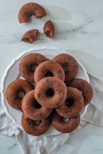 A top view of fresh sweet chocolate glazed donuts on the white tablecloth on the table