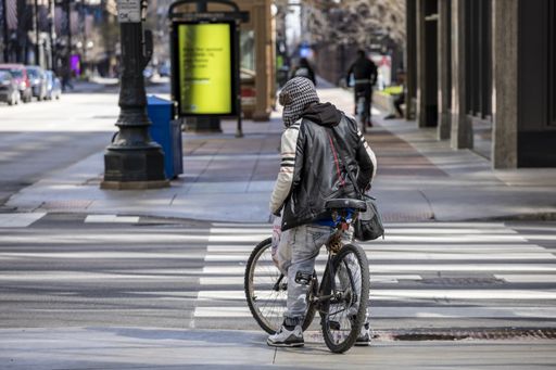 man biking in the empty streets in the downtown Chicago area during the Covid-19 virus pandemic. the city is closed due to quarantine and business