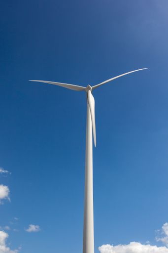 A vertical shot of a windmill under the sunlight and a blue sky at daytime - environmental concept