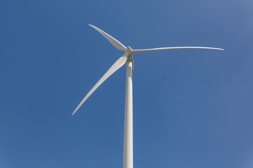 A low angle shot of a windmill under the sunlight and a blue sky at daytime - environmental concept