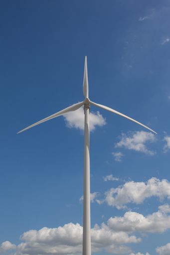 A vertical shot of a windmill under the sunlight and a blue sky at daytime - environmental concept