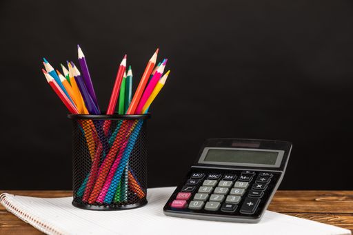 A stack of colored pencils with calculator and chalkboard