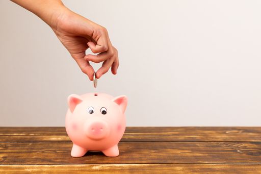 A close-up shot of a piggy bank with hand in a white background