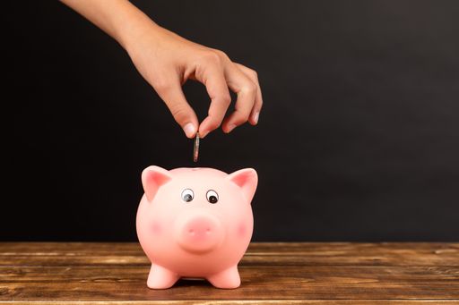 A close-up shot of a piggy bank with hand in a black background