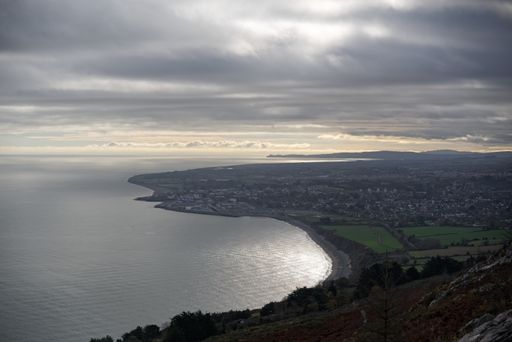 Aerial view of the calm Irish Sea and Greystones, a coastal town in County Wicklow, Ireland seen from the Bray Head summit on a cloudy winter day.