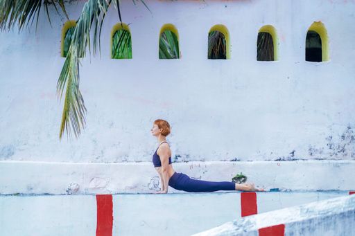A yogini in a blue outfit training near the white Hindu temple
