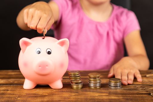 A close-up shot of a piggy bank with a child on a background