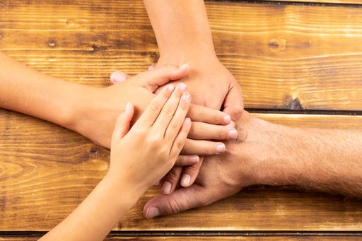 A top view of family hands on a wooden background
