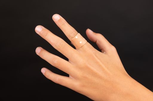 A close-up shot of plaster at a hand on a black background