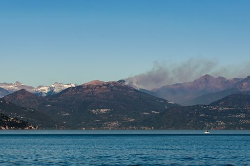 A beautiful view of Maggiore Lake with burning forests in the background from Stresa, Italy