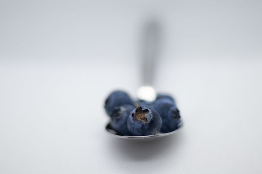 A selective focus shot of blueberries on a spoon isolated on a white background