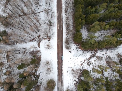 A top view of a traffic road with snowy forest